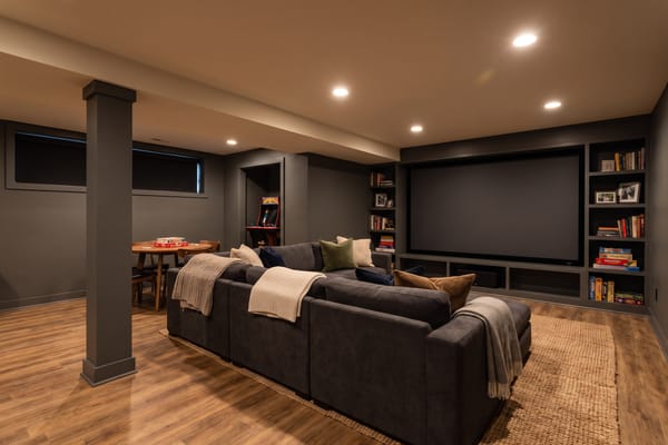 Finished basement home theater with sectional sofa and warm layered lighting